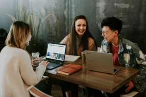 Employees sat around a desk smiling. They are satisfied with their jobs.