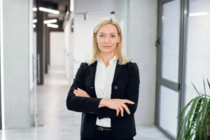 A chief technology officer stands facing the camera with her arms folded before heading into a meeting to negotiate her salary.