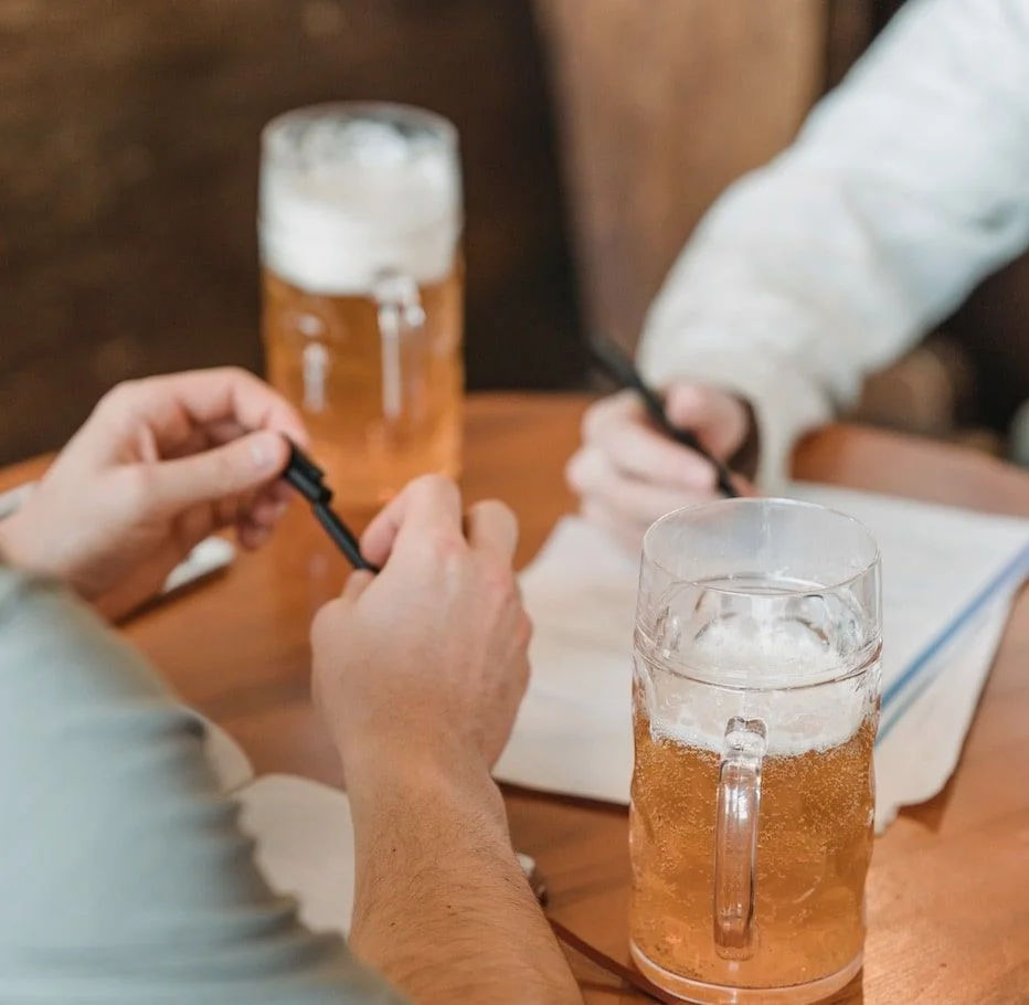 Two people with pints of beer are at a pub during a happy hour interview