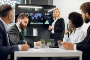 A team of managers is in a meeting reviewing insights from their SaaS management platform on a screen.