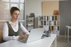 A payroll professional sitting at a computer using saas payroll software to complete payroll processing.