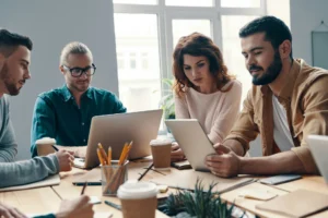 Colleagues sat around a table with coffees and iPads, discussing the meaning of SaaS business.